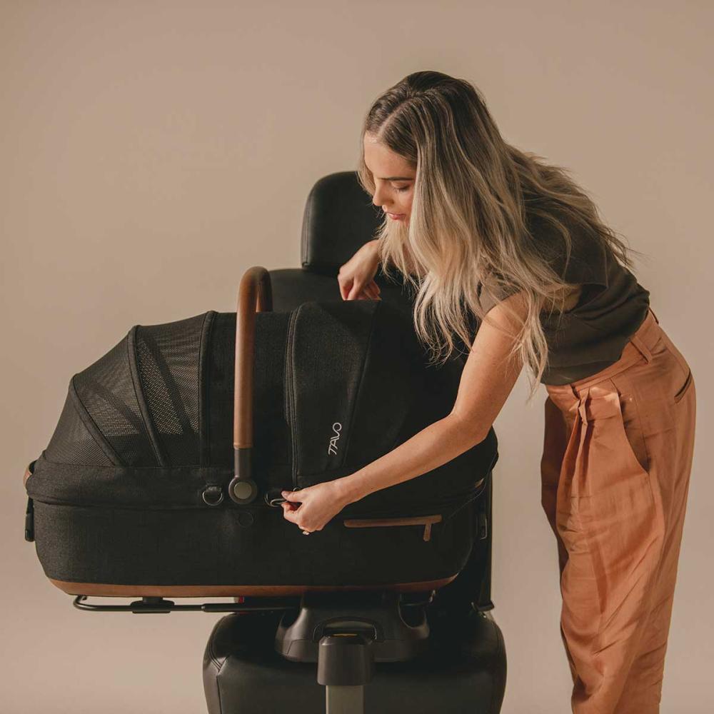 A brown dog sitting in the Maeve carrier in onyx fashion with open canopy.